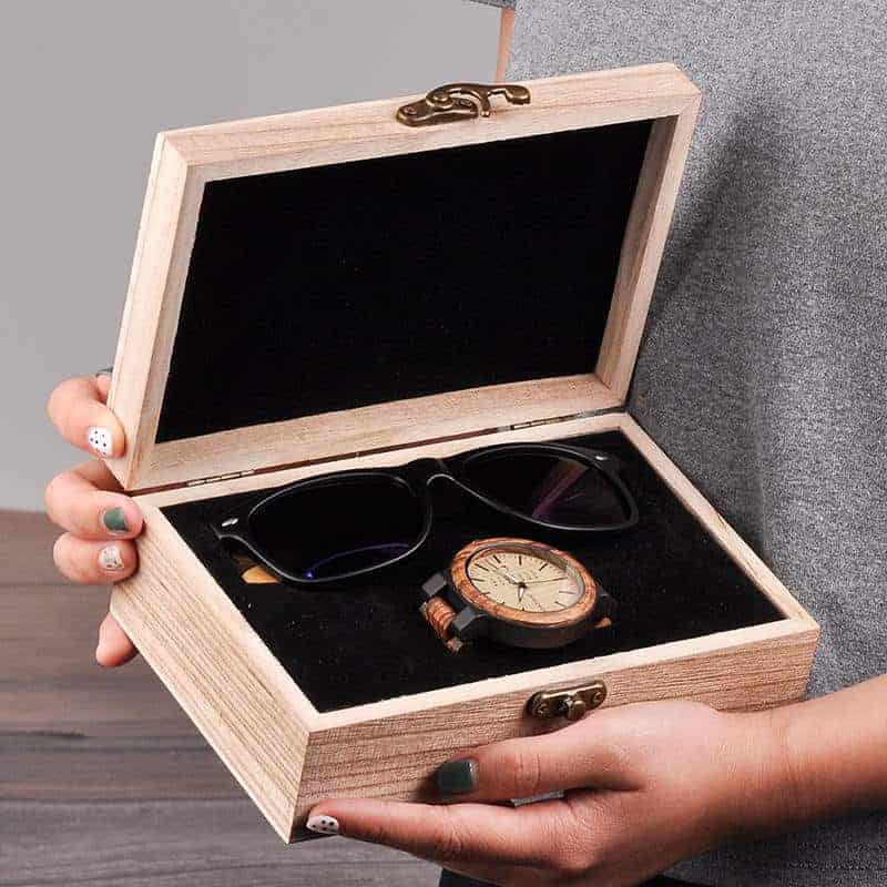 A lady opened a gift box with wooden glasses and a wooden watch
